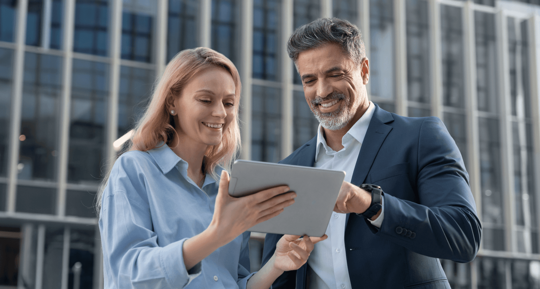 Mężczyzna i kobieta patrzący na dane na tablecie, uśmiechający się